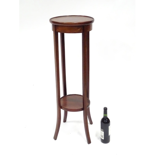 334 - An Edwardian mahogany jardiniere stand, with two circular tiers, decorated with boxwood stringing an... 