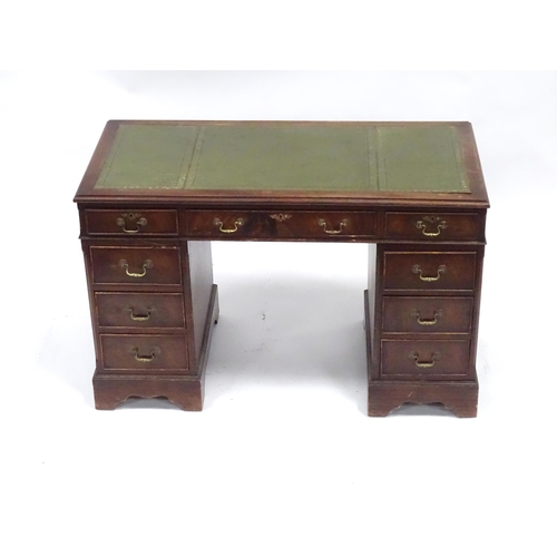 335 - A 20thC mahogany pedestal desk with nine drawers, the top with green tooled leather insert, the pede... 