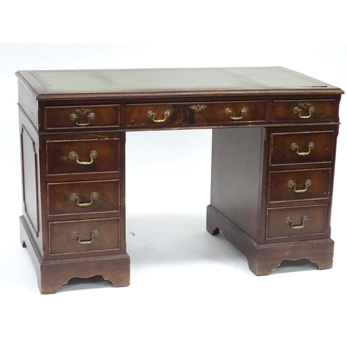 335 - A 20thC mahogany pedestal desk with nine drawers, the top with green tooled leather insert, the pede... 