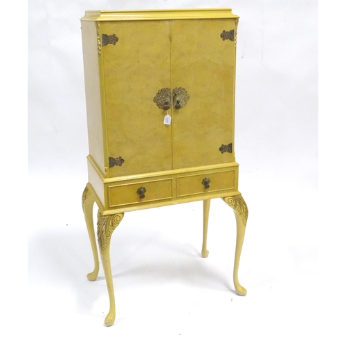 347 - A mid 20thC cocktail cabinet, the exterior with clouded yellow finish and oriental mounts. The upper... 