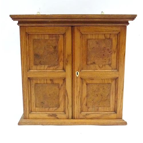 348 - A early 20thC wall cabinet, of ash construction with applied burr walnut panels to the doors. The in... 