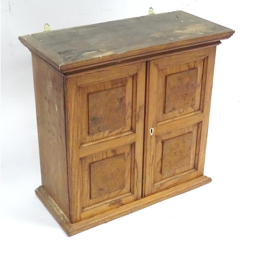 348 - A early 20thC wall cabinet, of ash construction with applied burr walnut panels to the doors. The in... 