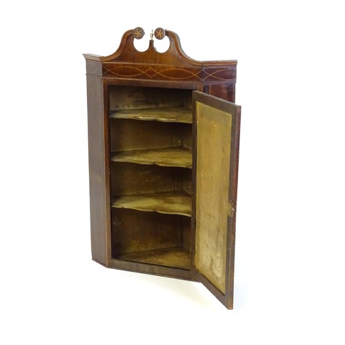 1 - A Georgian mahogany corner cupboard with a swans neck pediment decorated with starburst detailing, t... 