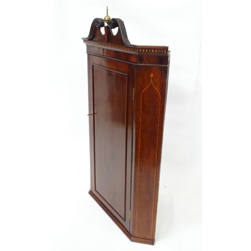 22 - A 19thC mahogany corner cupboard with carved pediment and brass finial, decorated with herringbone i... 