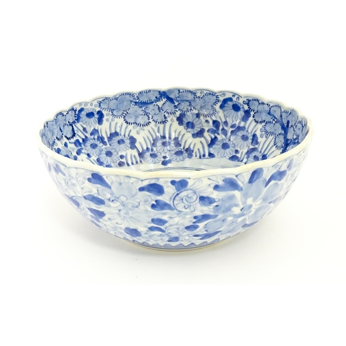 24 - A Japanese blue and white bowl with scalloped edge decorated with a central vase of flowers bordered... 