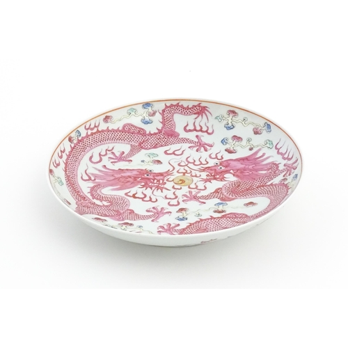 25 - A Chinese famille rose dragon dish with two dragons, flaming pearl and stylised clouds. The reverse ... 