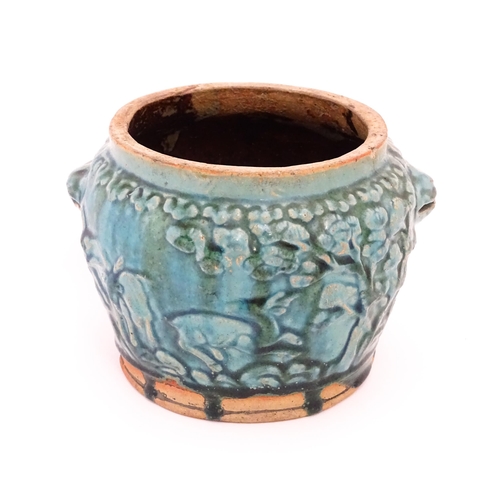 36 - A Shiwan style vase with a blue / green glaze and twin mask handles, the body decorated in relief wi... 