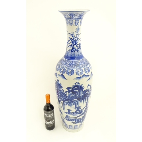 58 - A tall Chinese blue and white vase with a flared rim decorated with a landscape scene with flowers a... 