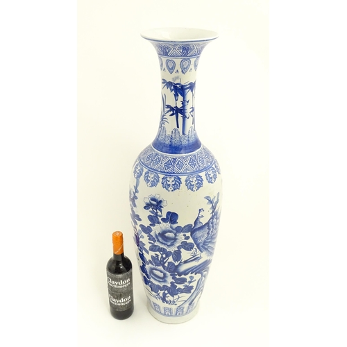 58 - A tall Chinese blue and white vase with a flared rim decorated with a landscape scene with flowers a... 