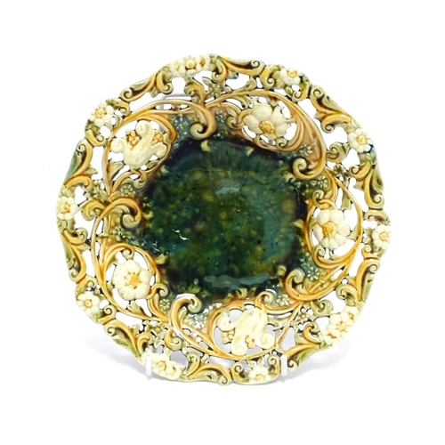 94 - A Linthorpe majolica plate with mottled green glaze to centre bordered by floral and pierced decorat... 