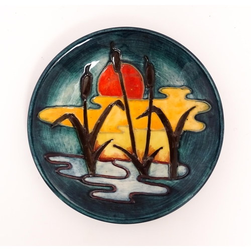 165 - A small Moorcroft plate decorated in the Reeds at Sunset pattern. Marked under. Approx. 4 3/4