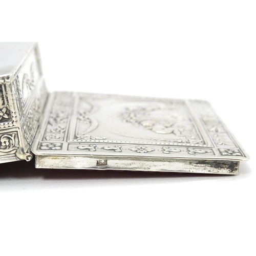 630 - A Continental silver box decorated with cherubs, floral and swag detail and opening to reveal a red ... 