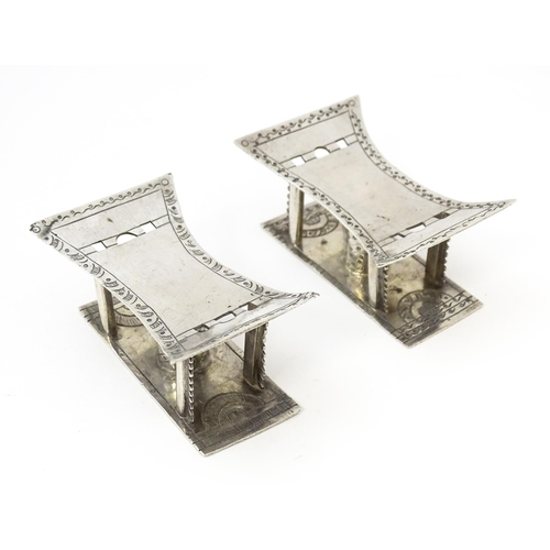 376 - A pair of white metal knife rests formed as African tribal Ashanti / Asante stools. Approx. 2 3/4