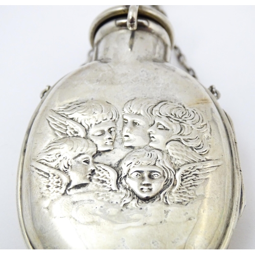 398 - A silver scent bottle cover with embossed angel detail, opening to reveal a green glass bottle withi... 