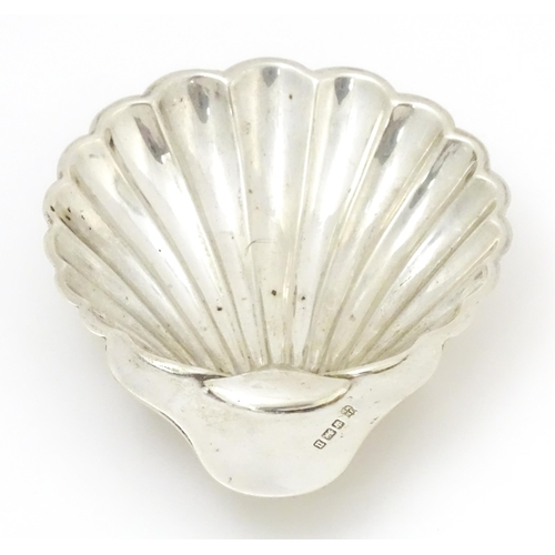 404 - A silver butter dish of scallop shell form raised on three ball feet, hallmarked Sheffield, 1912 mak... 