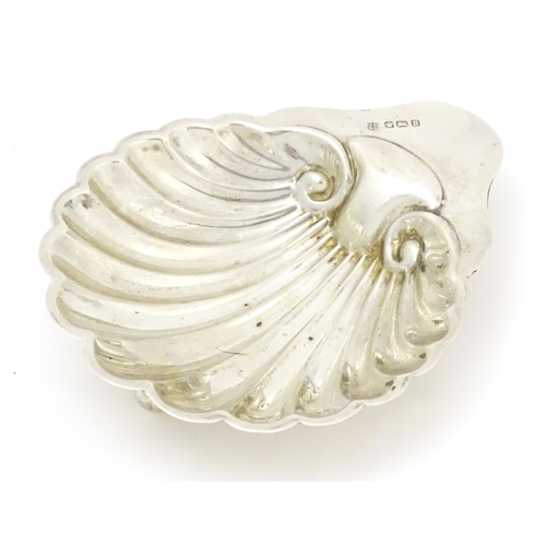 404 - A silver butter dish of scallop shell form raised on three ball feet, hallmarked Sheffield, 1912 mak... 