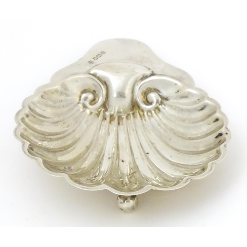 404 - A silver butter dish of scallop shell form raised on three ball feet, hallmarked Sheffield, 1912 mak... 