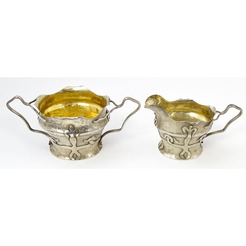 441 - An Arts & Crafts silver strawberry set comprising cream jug and sugar bowl with strapwork decoration... 