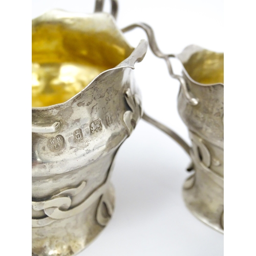 441 - An Arts & Crafts silver strawberry set comprising cream jug and sugar bowl with strapwork decoration... 