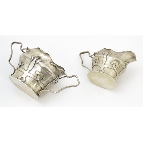 441 - An Arts & Crafts silver strawberry set comprising cream jug and sugar bowl with strapwork decoration... 