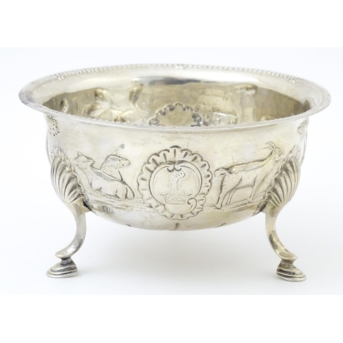 452 - An Irish silver bowl with embossed decoration depicting a cow and milkmaid, etc. raised on three fee... 