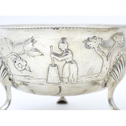 452 - An Irish silver bowl with embossed decoration depicting a cow and milkmaid, etc. raised on three fee... 