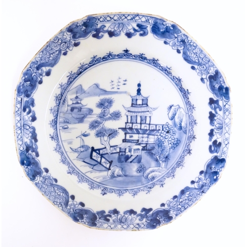 105 - A Chinese export blue and white plate depicting a river landscape scene with pagoda style buildings,... 