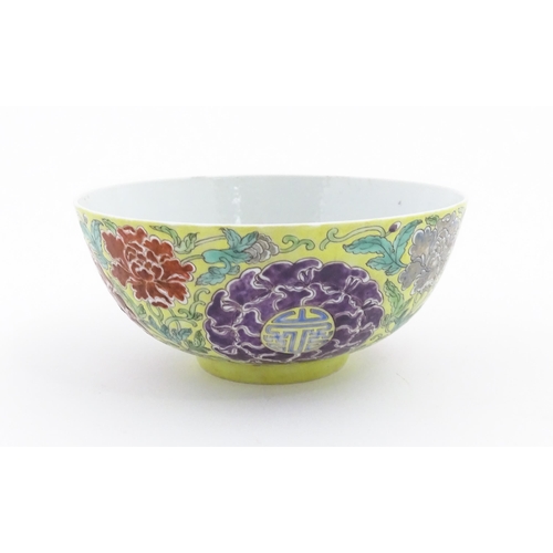 15 - A Chinese famille jeune bowl decorated with flowers, foliage and auspicious symbols. Character marks... 