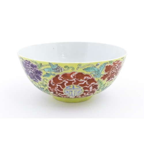 15 - A Chinese famille jeune bowl decorated with flowers, foliage and auspicious symbols. Character marks... 