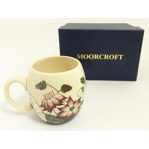 166 - A Moorcroft mug decorated in the Bramble pattern. With box. Marked under. Approx. 3 3/4
