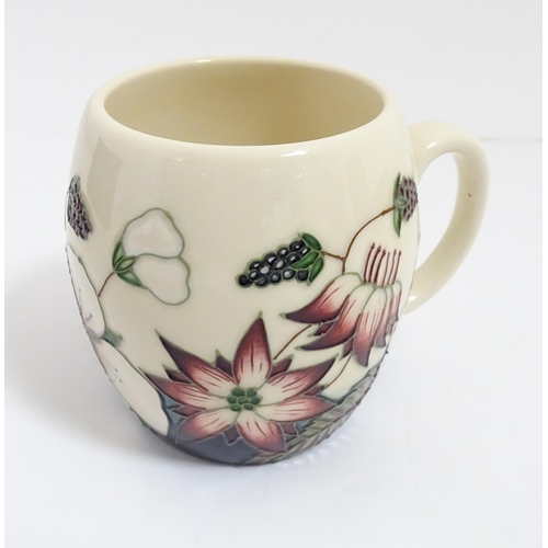 166 - A Moorcroft mug decorated in the Bramble pattern. With box. Marked under. Approx. 3 3/4