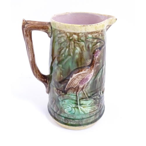 245 - A majolica jug with relief bird and foliate detail. Approx. 7 1/2