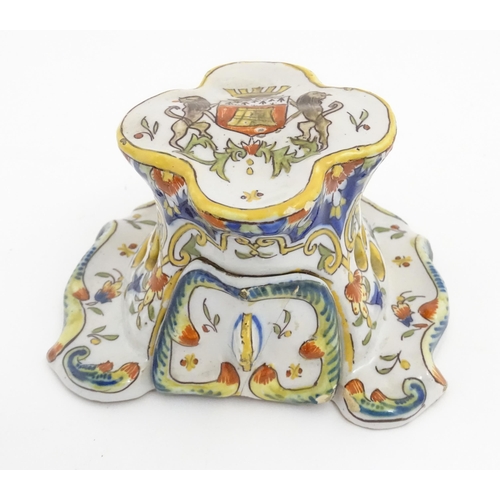 259 - A French faience inkwell of shaped form with armorial to top and scrolling foliate detail. Marked un... 