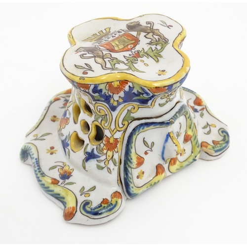 259 - A French faience inkwell of shaped form with armorial to top and scrolling foliate detail. Marked un... 