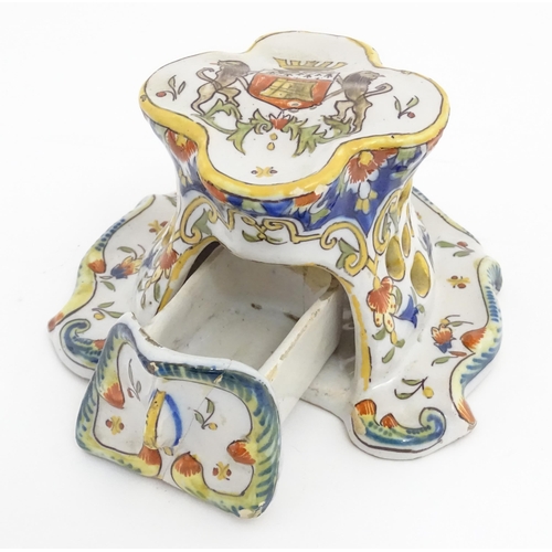 259 - A French faience inkwell of shaped form with armorial to top and scrolling foliate detail. Marked un... 