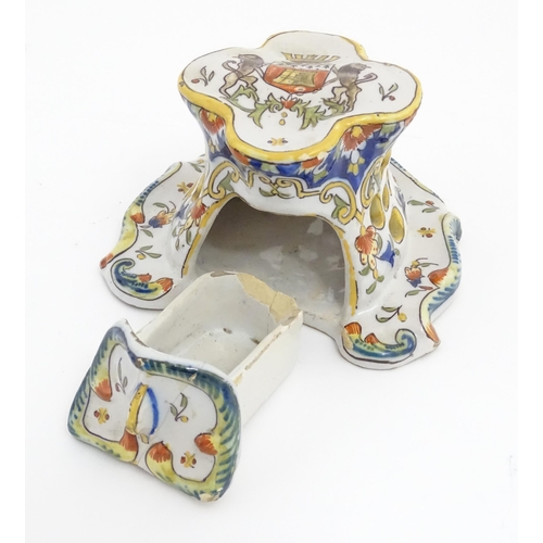 259 - A French faience inkwell of shaped form with armorial to top and scrolling foliate detail. Marked un... 