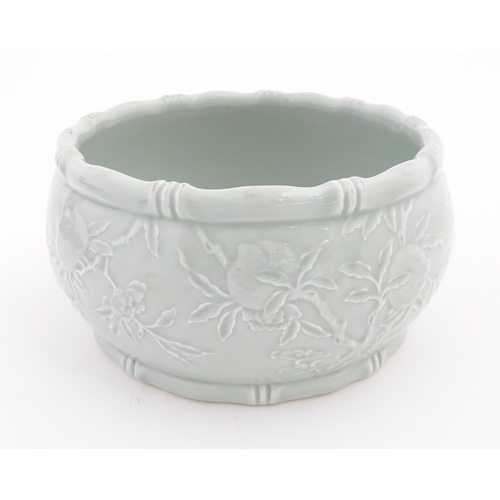 56 - A Chinese celadon planter decorated in relief with peaches and bat detail, and stylised bamboo rims.... 