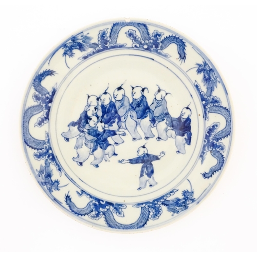 61 - A Chinese blue and white charger decorated with children playing bordered by dragons, with bamboo de... 