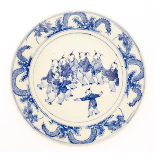 61 - A Chinese blue and white charger decorated with children playing bordered by dragons, with bamboo de... 