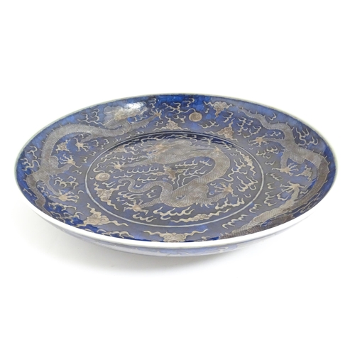 64 - A Chinese charger with blue ground decorated with dragons, flaming pearls and stylised clouds. Chara... 