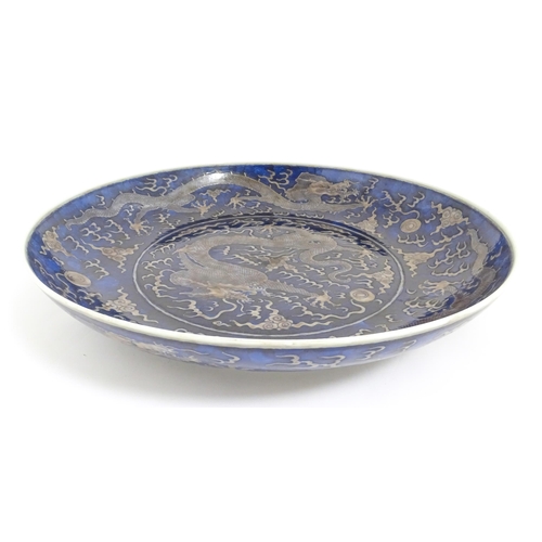 64 - A Chinese charger with blue ground decorated with dragons, flaming pearls and stylised clouds. Chara... 