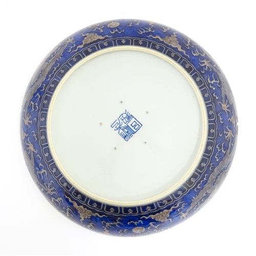 64 - A Chinese charger with blue ground decorated with dragons, flaming pearls and stylised clouds. Chara... 