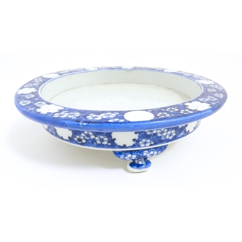 70 - A Chinese blue and white stand of circular form raised on three feet decorated with prunus flowers. ... 