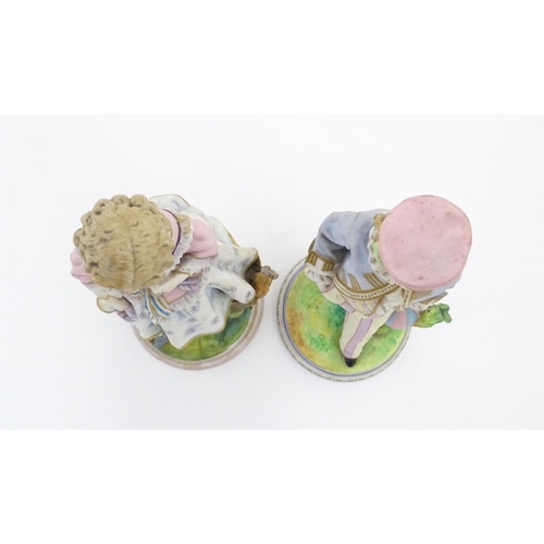 90 - A pair of bisque figures comprising a sailor boy and a girl with a floral dress. Approx. 9 1/4