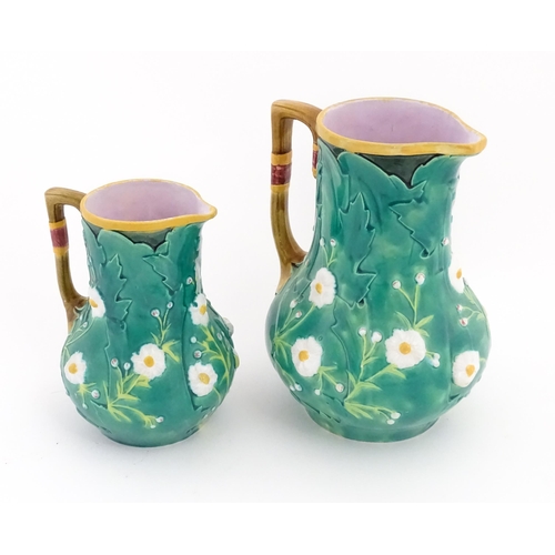 96 - Two majolica jugs with flowers and foliate decoration. One marked 'Minton' under. Largest approx. 8 ... 