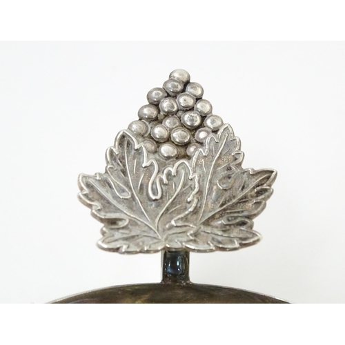 581 - A silver taste du vin with fruiting vine detail to thumb piece, hallmarked Birmingham 1957, maker Ga... 