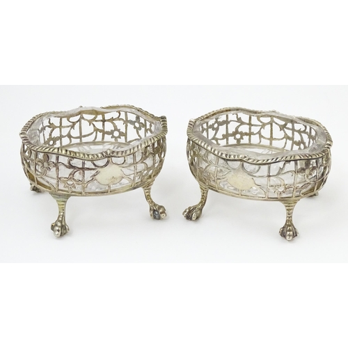 586 - A pair of Geo III silver salts with openwork decoration and raised on ball and claw feet, with clear... 