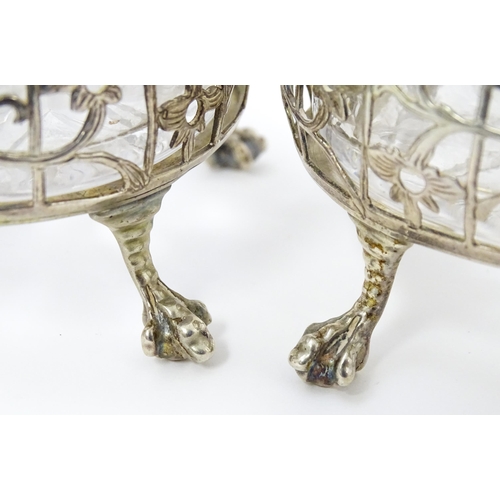 586 - A pair of Geo III silver salts with openwork decoration and raised on ball and claw feet, with clear... 