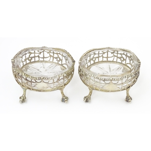 586 - A pair of Geo III silver salts with openwork decoration and raised on ball and claw feet, with clear... 