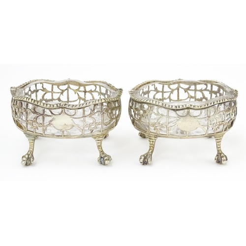 586 - A pair of Geo III silver salts with openwork decoration and raised on ball and claw feet, with clear... 